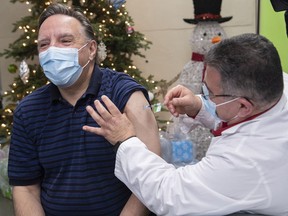 Quebec Premier François Legault receives a Pfizer-BioNTech COVID-19 booster vaccine dose from Georges Nader at the Olympic Stadium in Montreal on Monday, Dec. 27, 2021.