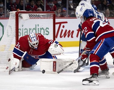 Montreal Canadiens goaltender Jake Allen (34) prepares to cover the puck as Montreal Canadiens right wing Cole Caufield (22) keeps Tampa Bay Lightning left wing Ross Colton (79) at bay during second period in Montreal on Tuesday, Dec. 7, 2021.