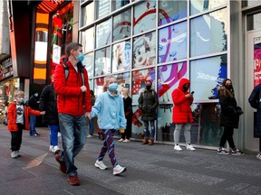People wear protective face masks to enter a store as new New York State indoor masking mandates went into effect amid the spread of the coronavirus disease (COVID-19) in New York City, U.S., December 14, 2021.