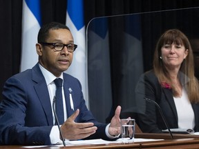 Quebec junior health minister Lionel Carmant speaks at a news conference after presenting legislation on youth protection, at the legislature in Quebec City, Wednesday, Dec. 1, 2021. Catherine Lemay, national director of youth protection, looks on.