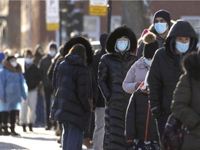 People wait in a long line at a COVID vaccination and testing site in the Saint-Henri district of Montreal, on Monday, January 3, 2022.