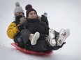 Ivanna Mora, left, and her sister Daniella enjoy the little snow available to them has the toboggan down the hill on Mount Royal on Jan. 6, 2022.