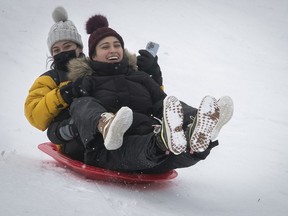 Ivanna Mora, left, and her sister Daniella toboggan down the hill on Mount Royal and Park Aves. Jan. 6, 2022.