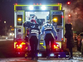 A woman watches paramedics load a COVID patient into an ambulance in January 2022.