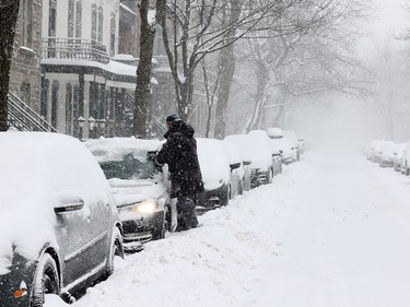 Ben Long clears snow off his car on Laporte St. during a snowstorm in Montreal Jan. 17, 2022.