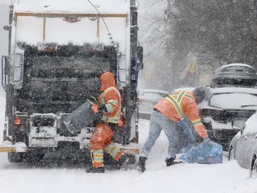 Garbage men do their job on St-Antoine St. during a snowstorm in Montreal Jan. 17, 2022.