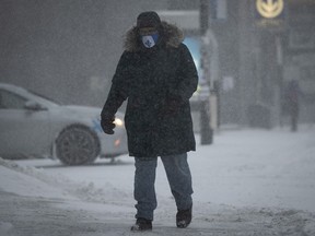 A Montrealer walks along the snow- covered sidewalk on Jean-Talon St. during the early morning part of the snowstorm on Monday January 17, 2022.