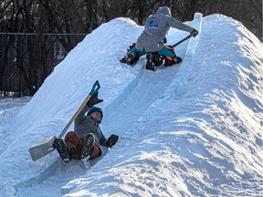 Snow and ice sculptor Melineige Beauregard slips, with Sèveline Beauregard up top, while working on an ice slide in Pointe-aux-Trembles on Tuesday Jan. 18, 2022.