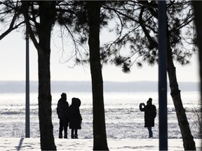 People stop to take pictures as they brave the cold for a walk along the lake shore in Dorval.