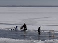 People play hockey on a section of ice on Lac St-Louis as they brave the cold in Pointe-Claire on Sunday.