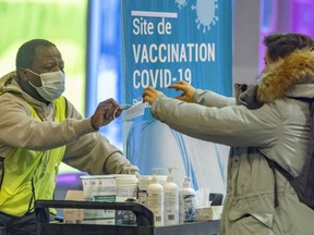 A woman is given a new mask at the COVID-19 vaccination centre in the Palais des Congrés in Montreal on Thursday, January 20, 2022.