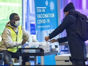 A man sanitizes his hands before being given a fresh mask at the COVID-19 vaccination centre in the Palais des congrès in Montreal on Thursday, Jan. 20, 2022.
