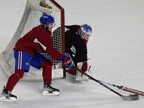 Goalie Kevin Poulin knocks defends against Jean-Sébastien Dea during a team practice in Laval on Friday, Jan. 21, 2022.