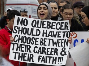 A woman holds a sign at a demonstration to denounce the Quebec government's Bill 21 in Montreal on Sunday, April 7, 2019.
