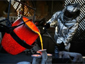 Workers in fire suits pour molten bronze metal into molds. The molten metal is too hot to be handled without protective equipment, but thanks to the Leidenfrost effect, a wet hand could be dipped into it briefly without causing burns. (Do not attempt this.)
