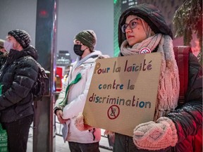 A woman holds a sign during a protest in Montreal on Dec. 15, 2021, in support of a teacher who wears a hijab and lost her job because of Bill 21.