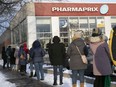 People wait in line to get a free COVID-19 rapid self-test kit at a pharmacy in Montreal on Monday, Dec. 20, 2021.