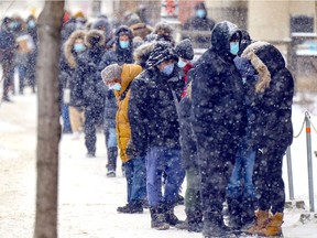 People wait in line during a snow squall outside the COVID-19 testing centre on Park Ave in Montreal Tuesday December 28, 2021. Difficulties in gaining access to testing, and now, restrictions of who can get a PCR data, mean case numbers are an under-estimate.