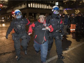 A demonstrator who was taking part in an anti-curfew protest in Montreal on Jan. 1, 2022, is taken away by police.