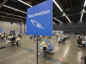 Health-care workers wait to vaccinate people at a COVID-19 clinic in Montreal in a file photo from Aug. 10, 2021. Canadians who have been vaccinated must be protected from those who have eschewed the shot, writes Tasha Kheiriddin. Quebec has announced a health tax on those who refuse to be vaccinated.