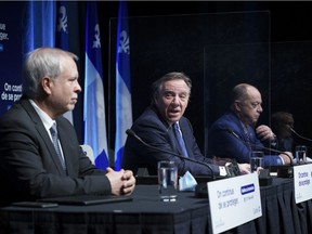 Dr. Luc Boileau, left, Quebec's new interim director of public health, is presented by Premier François Legault with Health Minister Christian Dubé during a news conference in Montreal, Tuesday, Jan. 11, 2022.