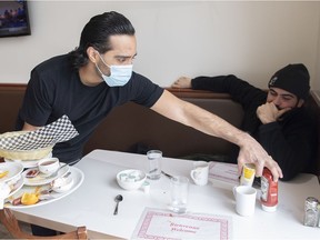 Ali Chaudhry, co-owner of Baba & Zazu clears a table at his restaurant as a customer looks on, Tuesday, January 25, 2022.