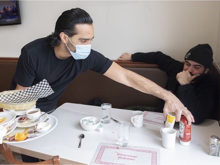  Ali Chaudhry, co-owner of Baba & Zazu clears a table at his restaurant as a customer looks on, Tuesday, January 25, 2022.