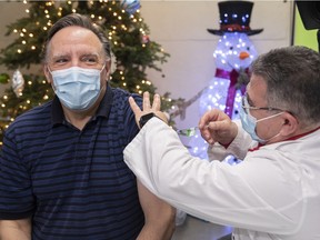 Premier François Legault receives a COVID-19 booster vaccine from Georges Nader at the Olympic Stadium on Dec. 27, 2021.