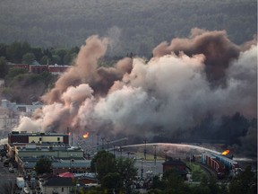 Smoke and fire rises over train cars after a train carrying crude oil derailed and exploded in the town of Lac-Mégantic, 100 kilometres east of Sherbrooke on Saturday, July 6, 2013.