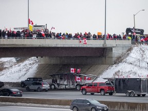 People gather on a highway overpass in Toronto to support truckers en route to Ottawa to protest vaccination mandates for cross-border truckers.