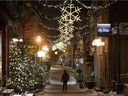 Ein einsamer Mann geht durch den Old Historic Champlain District in Quebec City, weniger als zwei Minuten vor Beginn der Ausgangssperre um 22 Uhr am 31. Dezember 2021.