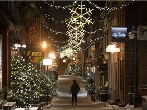 A lone man walks through the Old Historic Champlain district in Quebec City, less than two minutes before the start of the 10 p.m. curfew Dec. 31, 2021.