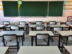 A school classroom with desks facing a green chalkboard.