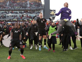 Canada's Richie Laryea, Alistair Johnston and Milan Borjan celebrate after defeating the United States in the World Cup CONCACAF Qualifiers at Tim Hortons Stadium in Hamilton, Ont., on Sunday, Jan. 30, 2022.