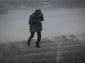 A pedestrian shields her face from blowing snow at Jean-Talon St. and De Chateaubriand Ave. on Jan. 17, 2022 during the first winter storm of the year.