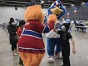 Kyle Appleby reçoit un high-five de la mascotte des Canadiens de Montréal Youppi!  à la clinique de vaccination du Palais des congrès le 5 février 2022. La mascotte du Rocket de Laval, Cosmo, était également présente pour faciliter l'expérience des enfants.