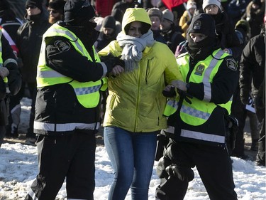 A woman was detained by police officers on  Grande Allée next to Quebec's National Assembly during a massive protest against COVID-19 vaccine and health restrictions on Saturday, Feb. 5, 2022.