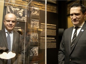 Quebec Environment and Anti-Racism Minister Benoit Charette, right, listens as he told the story of a small gift given to Fania Fainer for her 20th birthday while a prisoner at the Auschwitz concentration camp. Museum director Daniel Amar, left, looks on, in Montreal, on Friday, Feb. 4, 2022.