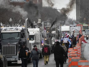 Protesters walk along René-Lévesque Blvd., as trucks race their engines near the National Assembly on the second day of a protest against COVID-19 vaccine and health restrictions held on Sunday, Feb. 6, 2022.