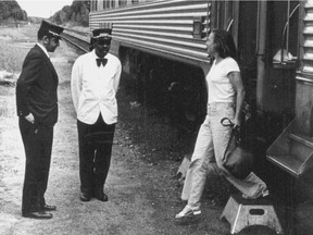 Rail workers watch as a woman alights from a train in Kenora, Ont., in the 1970s. The man in the white jacket would have been a porter. This is a detail from a vertical photo. The full photo follows the text.