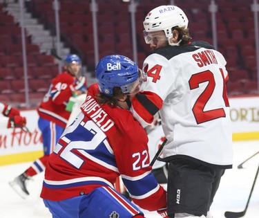 Montreal Canadiens' Cole Caufield takes an elbow to the face from New Jersey Devils' Ty Smith during first period in Montreal, Tuesday, Feb. 8, 2022.