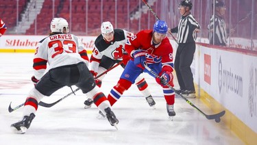 Montreal Canadiens' Ben Chiarot pushes the puck past New Jersey Devils' Ryan Graves and Nathan Bastien during first period in Montreal Tuesday, Feb. 8, 2022.