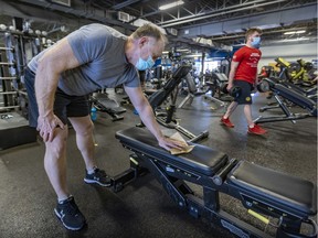 Michael Chaif disinfects a bench after using it while working out at Klub 20 in Beaconsfield on Feb. 14, 2022, the day gyms were allowed to reopen at half capacity.