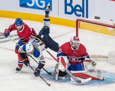 St. Louis Blues centre Brayden Schenn (10) is upended by Montreal Canadiens defenseman Brett Kulak (77) next to Montreal Canadiens goaltender Sam Montembeault (35) during third period in Montreal on Thursday, Feb. 17, 2022.