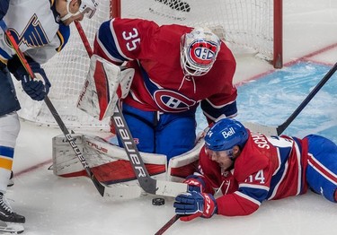 Montreal Canadiens defenseman Corey Schueneman (64) helps Canadiens goaltender Sam Montembeault (35) cover up the puck with St. Louis Blues left wing Pavel Buchnevich (89) looking on during second period in Montreal on Thursday, Feb. 17, 2022.