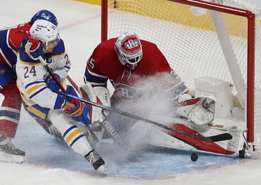 Montreal Canadiens goaltender Sam Montembeault makes save on Buffalo Sabres' Dylan Cozens (24) while Montreal Canadiens' Alexander Romanov (27) tries to hold back the play during third period NHL action in Montreal on Wednesday, Feb. 23, 2022.