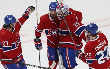 Montreal Canadiens goaltender Sam Montembeault celebrates his shutout against the Buffalo Sabres with teammates, Alexander Romanov (27), Brett Kulak (77) and Cole Caufield (22) following third period NHL action in Montreal on Wednesday, Feb. 23, 2022.