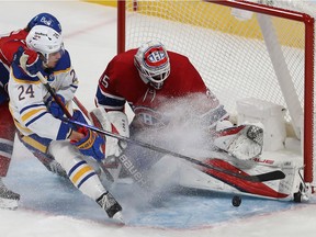 Montreal Canadiens goaltender Sam Montembeault makes a save on the Buffalo Sabres' Dylan Cozens (24) while Montreal's Alexander Romanov (27) tries to hold back the play, during third-period NHL action in Montreal on Wednesday February 23, 2022.