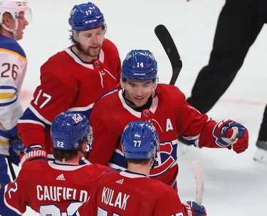 Montreal Canadiens' Nick Suzuki (14) celebrates his goal against the Buffalo Sabres, with teammates Josh Anderson (17), Cole Caufield (22) and Brett Kulak (77) during first-period NHL action in Montreal on Wednesday, Feb. 23, 2022.