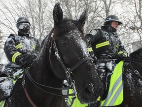 Mounted Montreal police officers talk with people after a snow squall at the Plaisirs d'hiver on Saturday, Feb. 19, 2022, in the Pierrefonds-Roxboro borough.